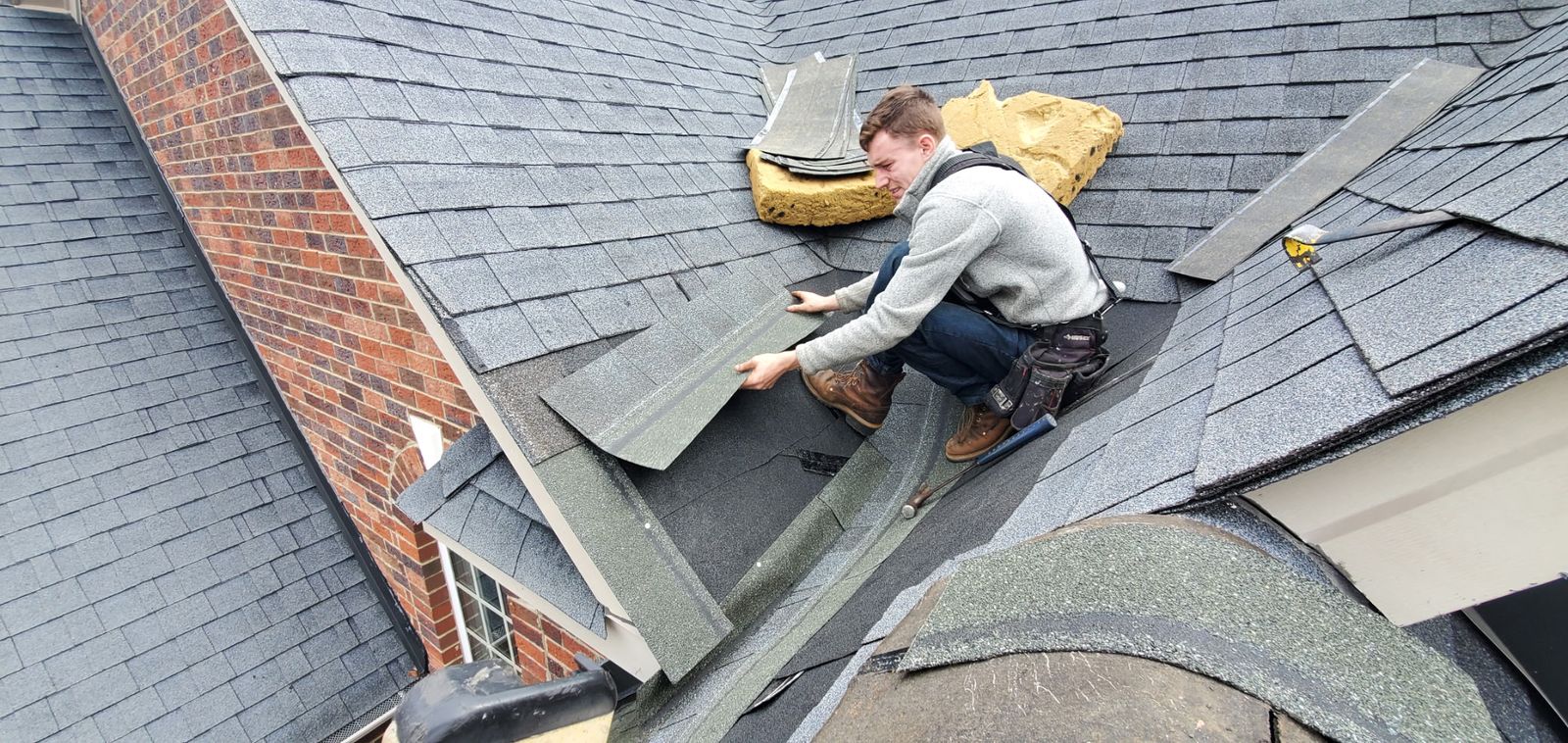 Roofing technician hand-nailing a shingle valley on an Atlanta home